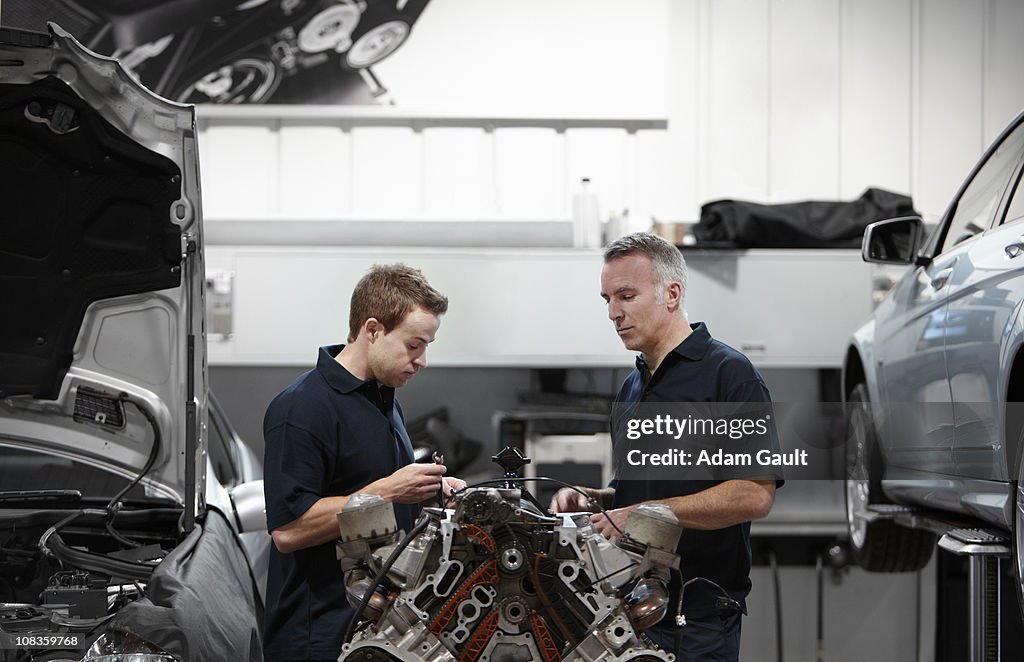 Mechanics working on engine in auto repair shop