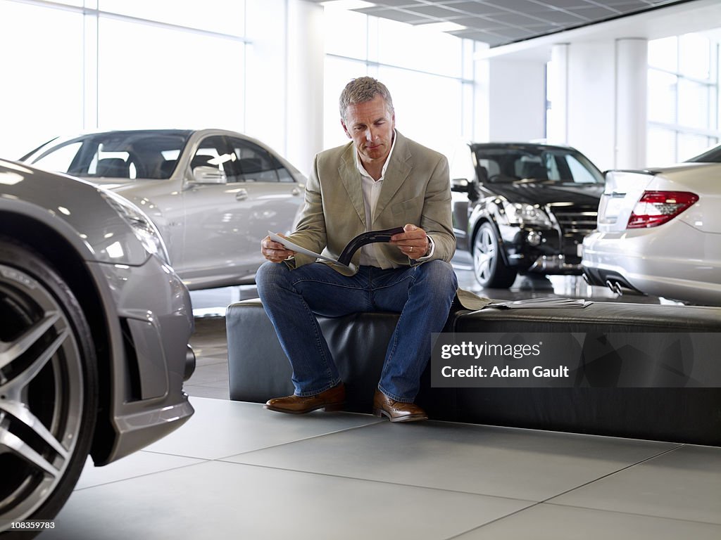 Man looking at brochure in automobile showroom