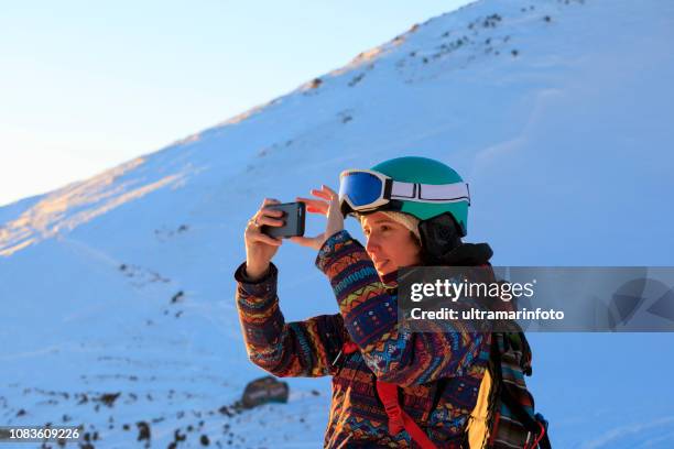vrouw skiër met smartphone op zonnige skigebied amateur wintersporten. zonsondergang op de top - extreem skiën stockfoto's en -beelden