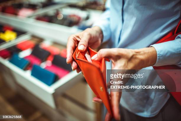 senior onherkenbaar vrouw op zoek naar een rode portemonnee in een winkel voor tassen en portemonnees - red leather purse stockfoto's en -beelden