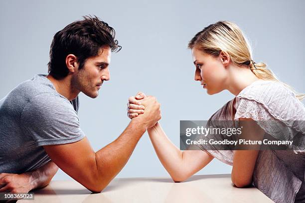 pareja joven brazo lucha contra el fondo gris - wrestling fotografías e imágenes de stock