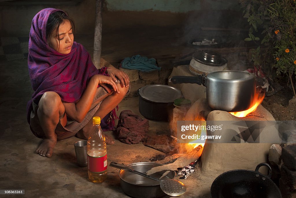 Poor, Indian girl cooking food on a clay stove