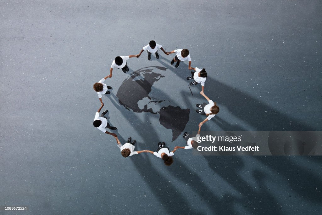 School children in uniforms standing in circle & holding hands