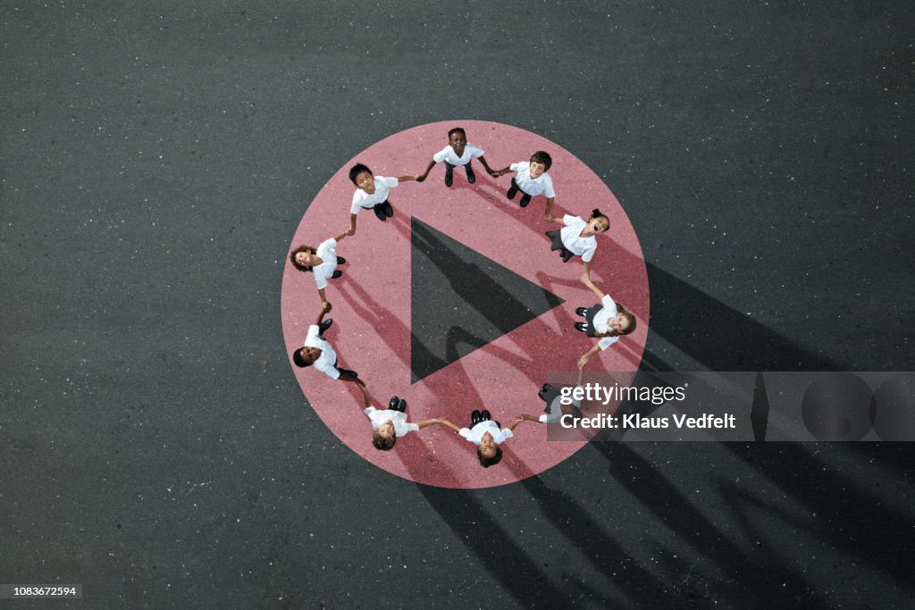School children in uniforms standing in circle & holding hands