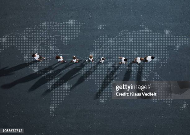 school children in uniforms walking in row across world map - weltbevölkerung stock-fotos und bilder