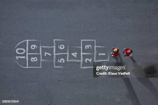 school girls standing in front big hopscotch & looking up in camera - aerial view of childs playground stock pictures, royalty-free photos & images