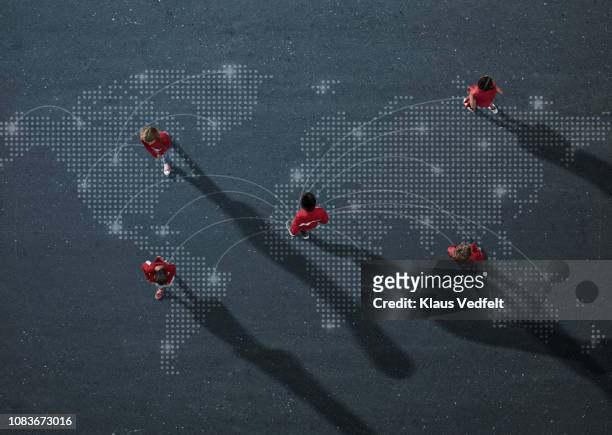 group of red dressed children walking and standing on world map - five people foto e immagini stock