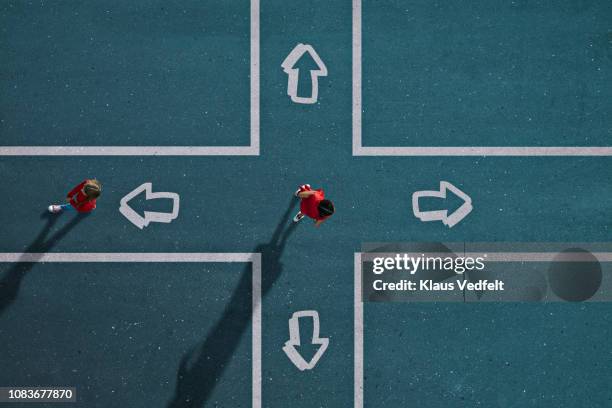 children dressed in red choosing direction at painted crossroad - choix photos et images de collection