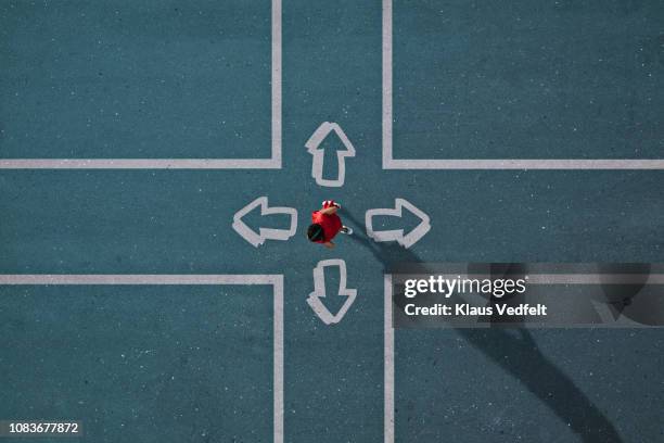 girl dressed in red choosing direction at painted crossroad - wahlmöglichkeit stock-fotos und bilder