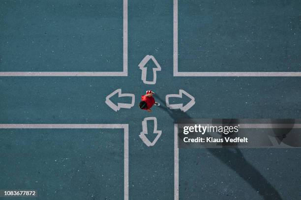 girl dressed in red choosing direction at painted crossroad - emprender fotografías e imágenes de stock