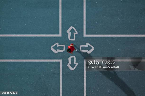 girl dressed in red choosing direction at painted crossroad - opportunity stock pictures, royalty-free photos & images
