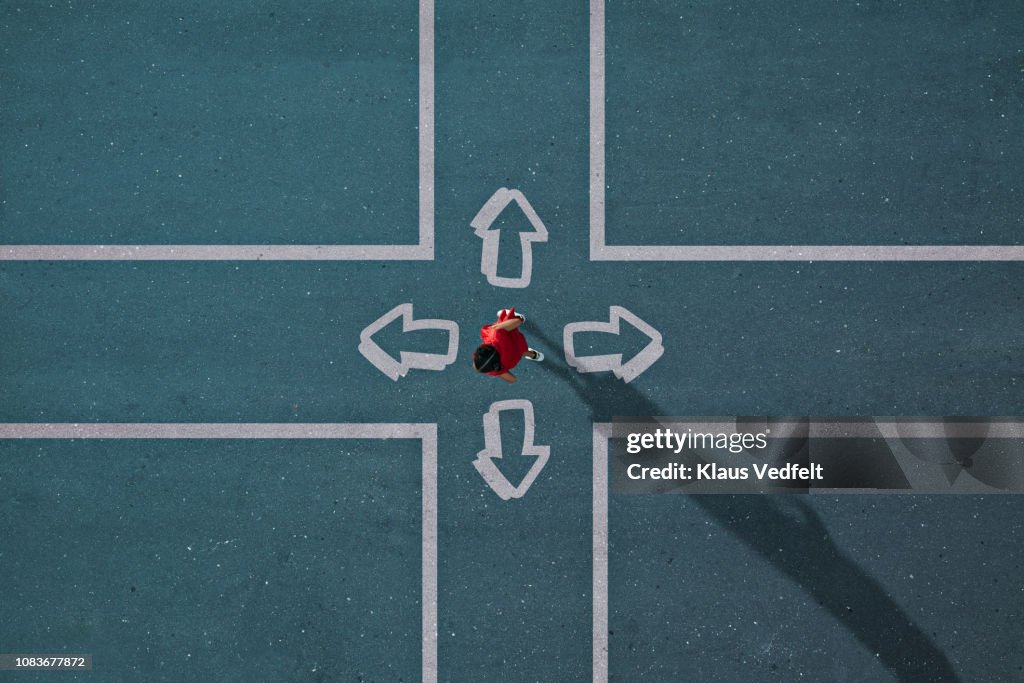 Girl dressed in red choosing direction at painted crossroad