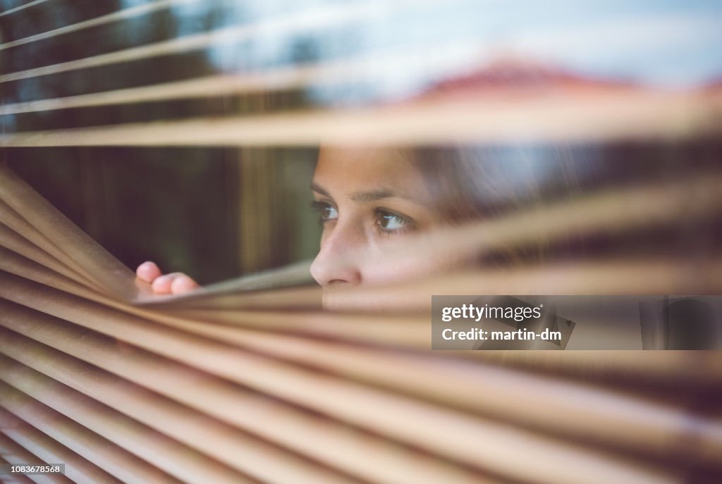 Unglückliche Frau guckt durchs Fenster