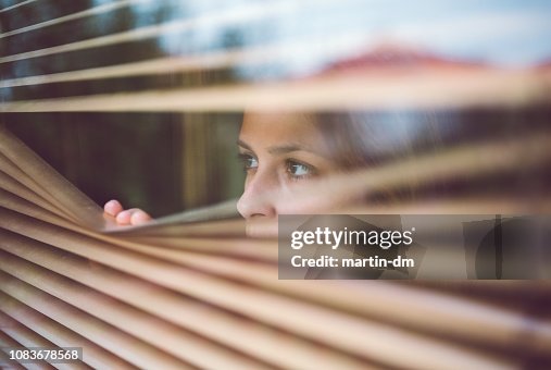 Unhappy woman peeks through the window Unhappy woman peeks through the window