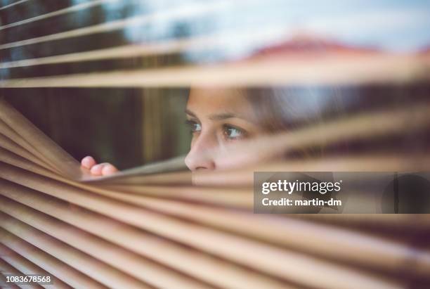 unhappy woman peeks through the window - doom patrol stock pictures, royalty-free photos & images