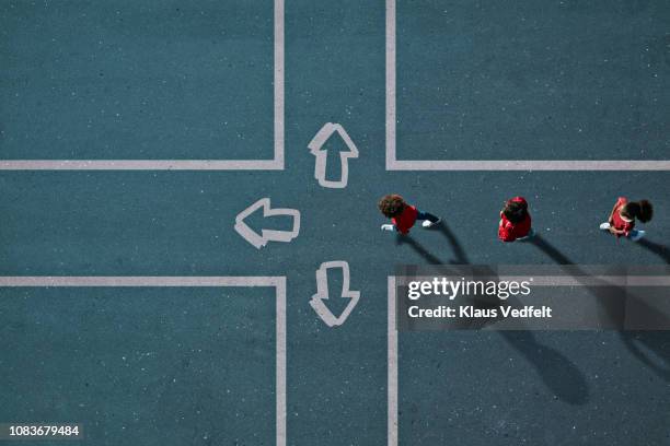 children dressed in red approaching painted crossroad with arrows - school boy girl stock-fotos und bilder