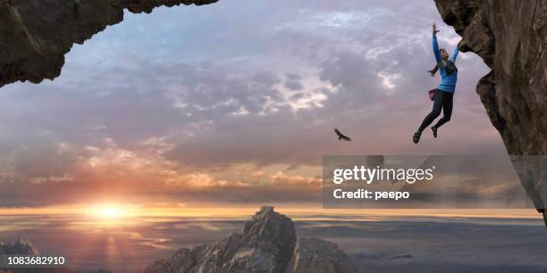 frau free climbing steilen felsen stehen hoch oben bei sonnenaufgang - überhängend stock-fotos und bilder