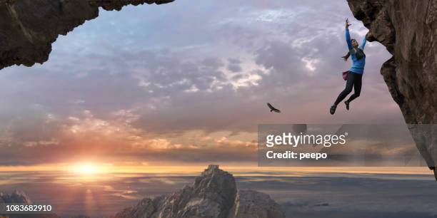 woman free climbing sheer rock face high up at sunrise - extreme sports female stock pictures, royalty-free photos & images