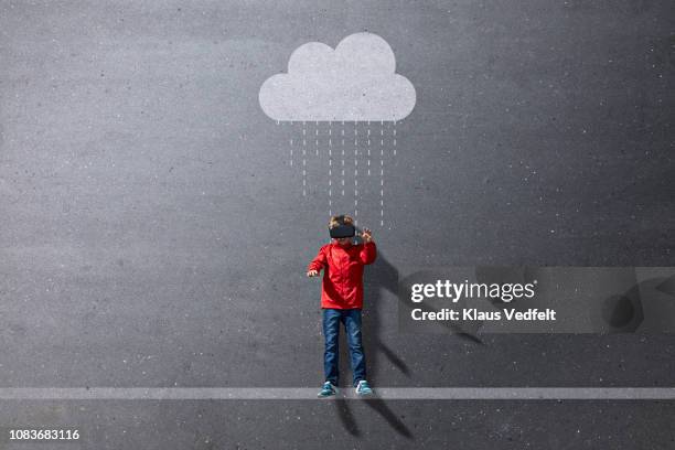 boy wearing vr goggles standing under imaginary painted rain cloud - negative photo illusion stock pictures, royalty-free photos & images