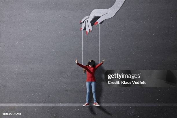 girl wearing vr goggles laying on background with imaginary painted puppeteer hand - faden hände stock-fotos und bilder