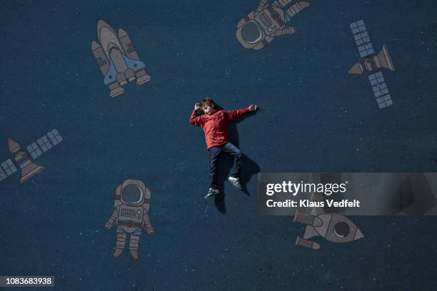 boy laying on painted imaginary background among space travel objects - child drawing job stock pictures, royalty-free photos & images