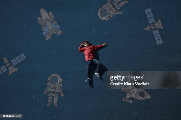 boy laying on painted imaginary background among space travel objects - child drawing job imagens e fotografias de stock