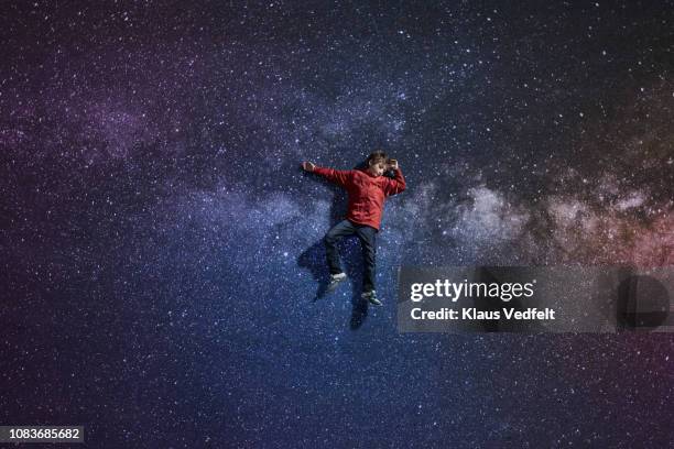 boy laying on painted imaginary background of space with stars - schwerelos stock-fotos und bilder