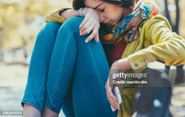 ragazza con il cuore spezzato seduta sola fuori - farfalle nello stomaco foto e immagini stock