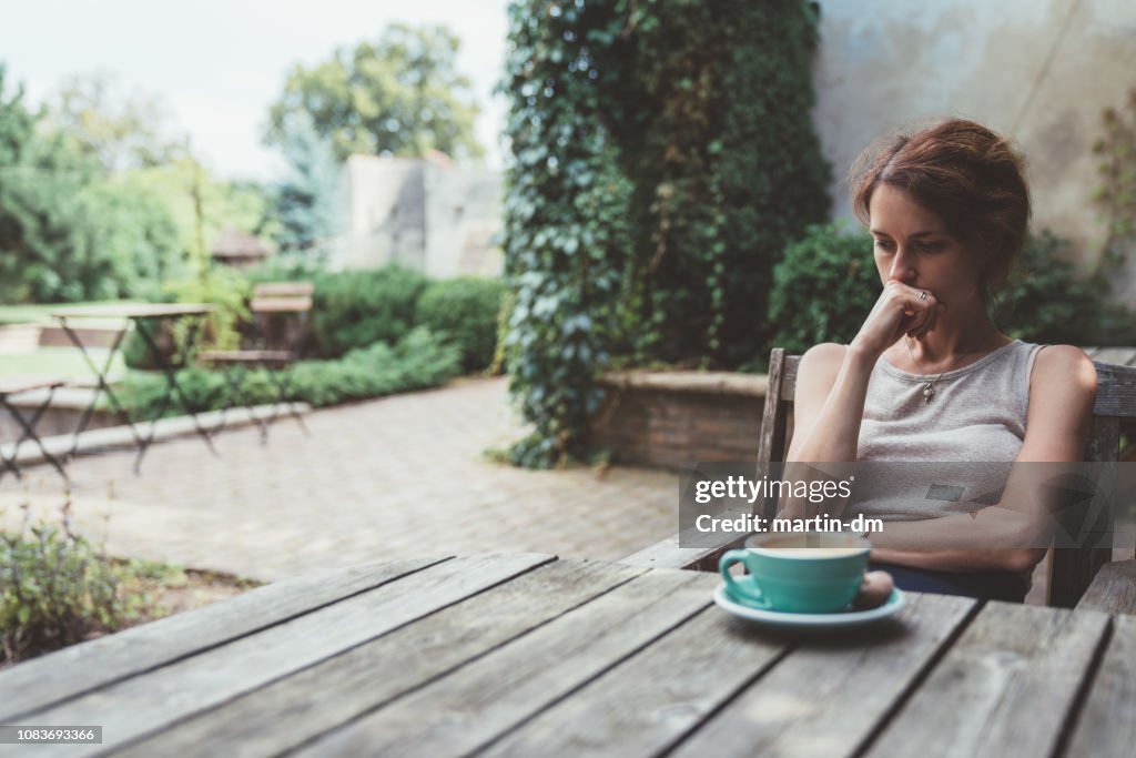 Depressed woman drinking coffee at the veranda