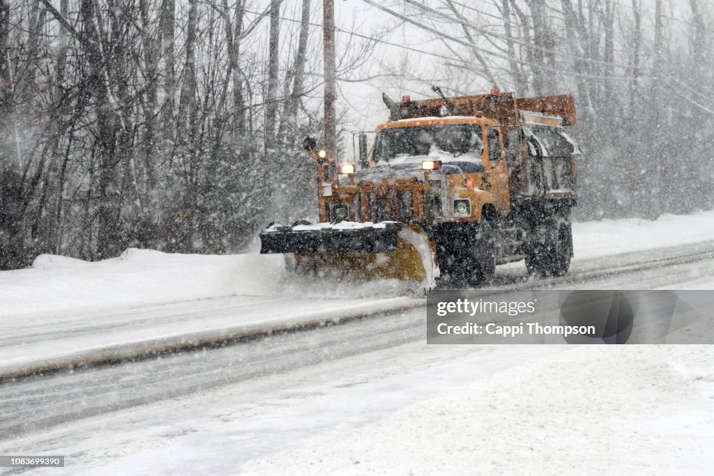 Municipal plow truck plowing snow off roadways in Laconia, New Hampshire USA