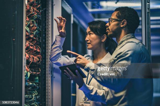 female asian it technician explaining network connection to a novice engineer - it support server stock pictures, royalty-free photos & images