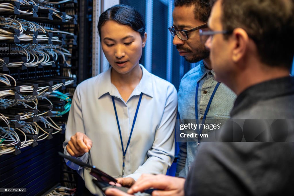 IT engineers looking at a digital tablet next to a server