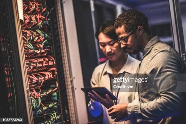 engenheiros it usando um tablet digital na sala dos servidores de um data center - programador de informática - fotografias e filmes do acervo