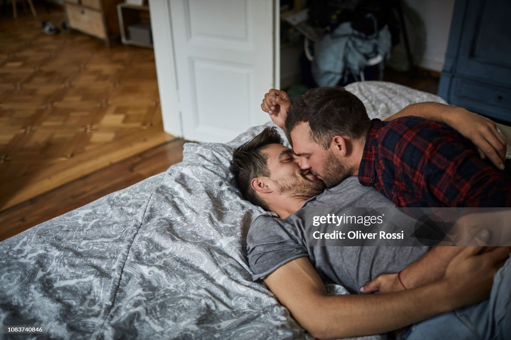 Affectionate gay couple kissing in bed at home