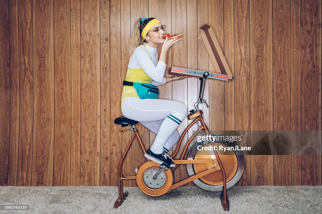 Mulher de bicicleta de exercício estilo retro dos anos oitenta Era comer Pizza