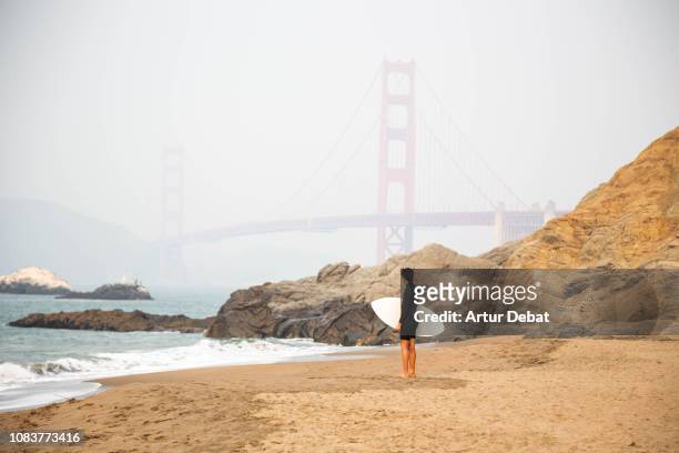 surfer with the golden gate bridge from baker beach. - baker beach stock pictures, royalty-free photos & images