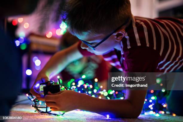 little boy preparing christmas lights on christmas tree - plugging in holiday lights stock pictures, royalty-free photos & images