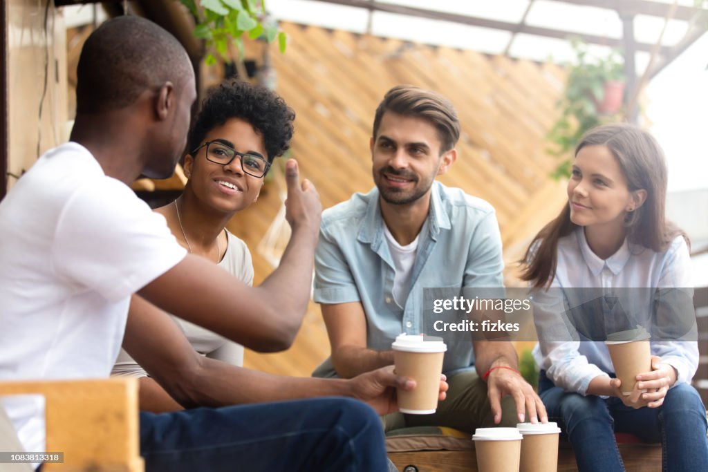 African American man showing thumb up to friends in cafe