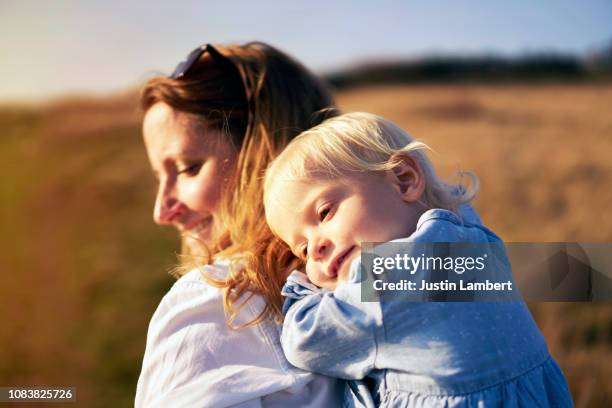 daughter having a piggyback ride on a weekend break with coastal walk in love feeling protected and a special bond and moment of true love - moment of silence stockfoto's en -beelden