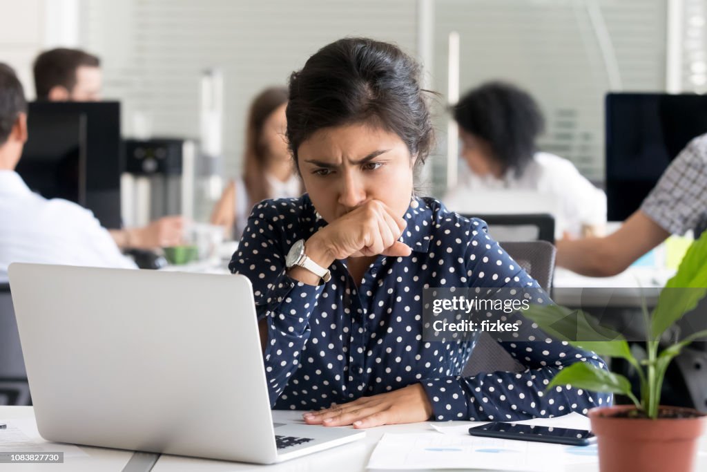Focused Indian businesswoman looking at laptop screen