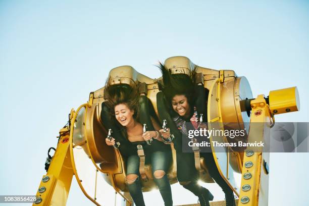 laughing female friends spinning upside down on amusement park ride - diversión fotografías e imágenes de stock