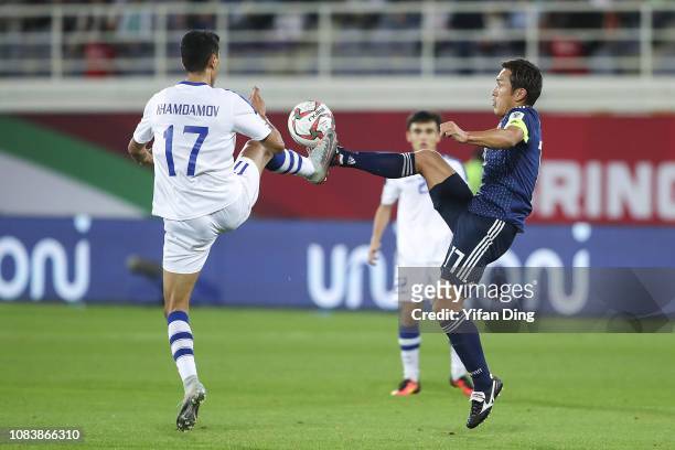 Toshihiro Aoyama of Japan and Dostonbek Khamdamov of Uzbekistan fight for the ball during the AFC Asian Cup Group F match between Japan and...