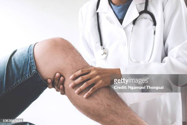 midsection of doctor holding patient leg in clinic - human knee stock pictures, royalty-free photos & images