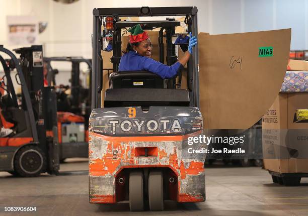 Postal service mail handler Louvane Virgile drives a forklift carrying packages for sorting at the U.S. Postal service's Royal Palm Processing and...