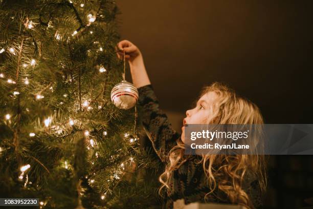 niña, decorar árbol de navidad con adornos - christmas trees fotografías e imágenes de stock