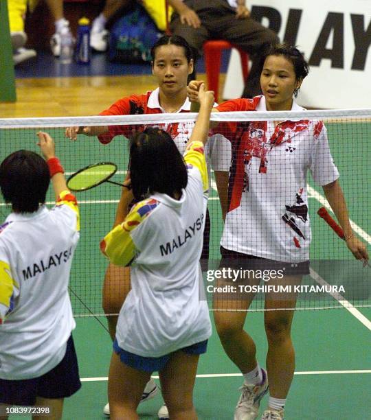 Deyana Lomban and Elysa Nathanael of Indonesia reach to shake hands with Malaysia's Lim Pek-Siah and Chor Hooi-Yee after winning their doubles match...