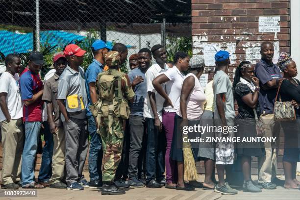 Zimbabwean soldier watches shoppers lining up, in Bulawayo on January 17, 2019 as order is slowly restoring. - Nationwide demonstrations erupted on...