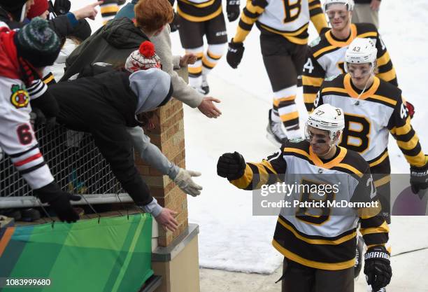 John Moore of the Boston Bruins high fives fans during an intermission for the 2019 Bridgestone NHL Winter Classic game against the Chicago...