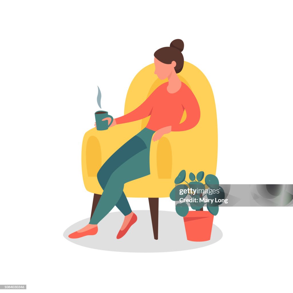 Dreamy Woman sitting in the chair At Home with a cup of tea or coffee.
