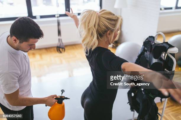 trainer preparing lady for ems training - prop stock pictures, royalty-free photos & images